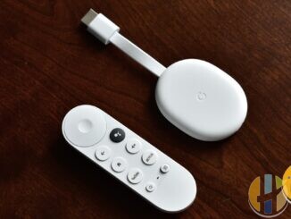 Real Chromecast with Google TV stick and Bluetooth remote on a wooden desk — living-room streaming kit for catch-up and catalogue apps; no EE branding.