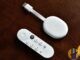 Real Chromecast with Google TV stick and Bluetooth remote on a wooden desk — living-room streaming kit for catch-up and catalogue apps; no EE branding.