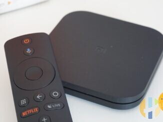 Real Xiaomi Mi Box S Android TV streaming box and Bluetooth remote on a white desk — generic Android TV hub hardware of the kind used for Freely and catalogue apps; no Vodafone branding.