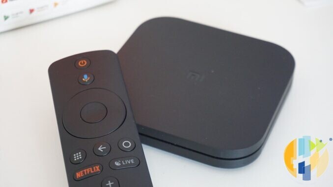 Real Xiaomi Mi Box S Android TV streaming box and Bluetooth remote on a white desk — generic Android TV hub hardware of the kind used for Freely and catalogue apps; no Vodafone branding.