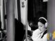 Documentary photo of a woman on public transit looking at her phone — travel and public-network mobile context without VPN brand forge.
