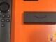 Real Amazon Fire TV Stick and Alexa Voice Remote on an orange display surface — everyday second-room streaming stick alternative; no TalkTalk or YouView forged marks.