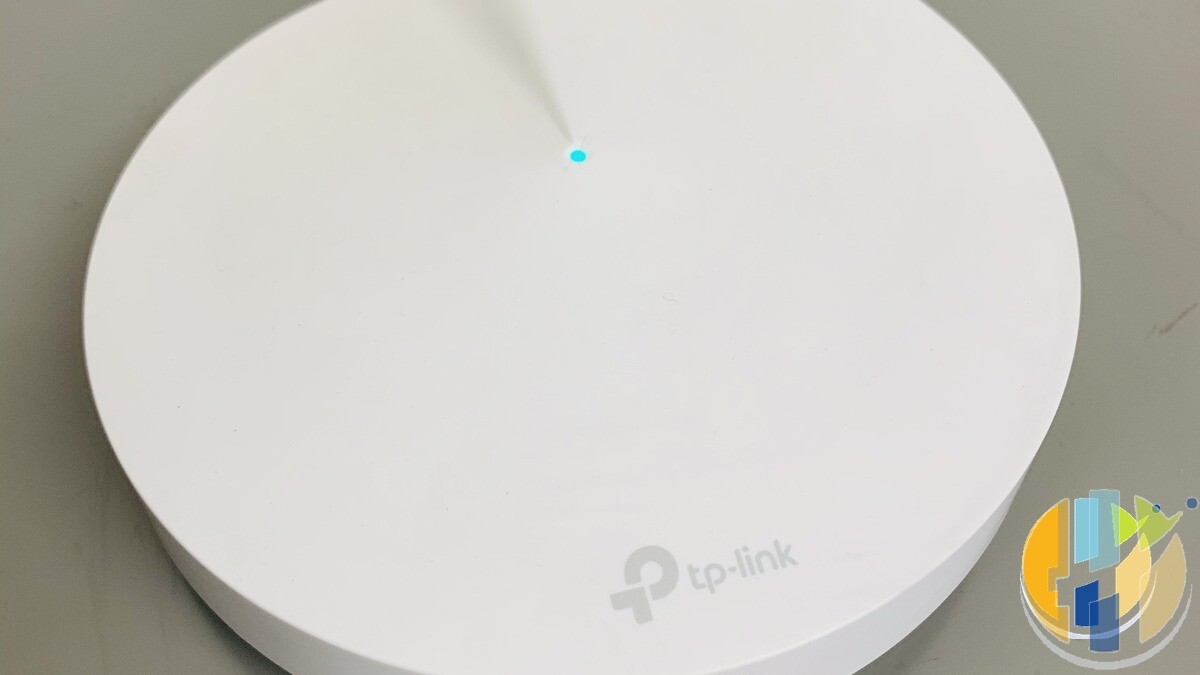 Real TP-Link Deco mesh Wi-Fi node on a desk with cyan status LED — mesh placement is a common fix for stick buffering in UK living rooms.