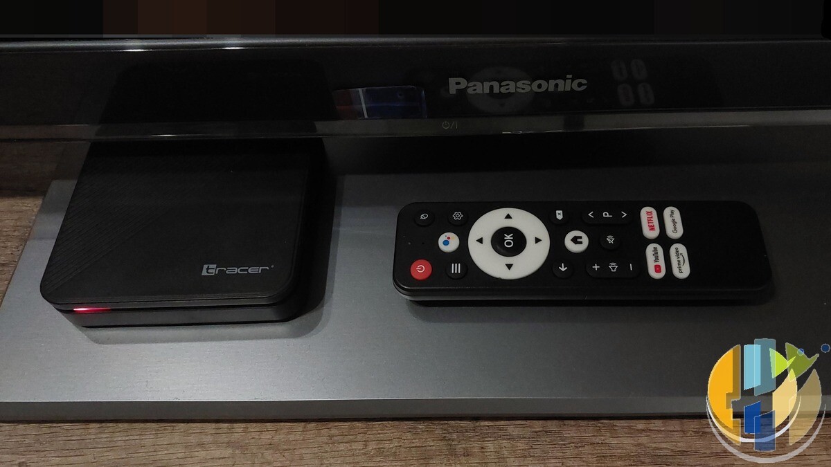 Real Android TV set-top box (Tracer) and Google Assistant remote on a Panasonic TV stand — everyday Android TV living-room kit without Vodafone marks.