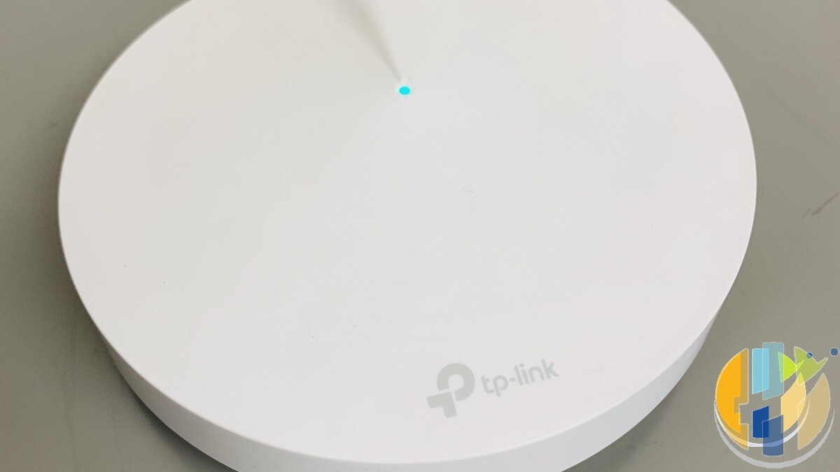 Real TP-Link Deco mesh Wi-Fi node on a desk with cyan status LED — everyday mesh placement kit for UK multi-room streaming.