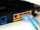 Two blue Ethernet cables plugged into the LAN ports on the back of a black home router