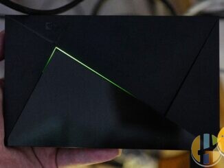 NVIDIA SHIELD TV media player held in a hand with its green light strip glowing