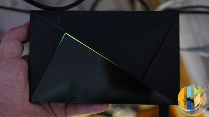 NVIDIA SHIELD TV media player held in a hand with its green light strip glowing