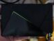NVIDIA SHIELD TV media player held in a hand with its green light strip glowing