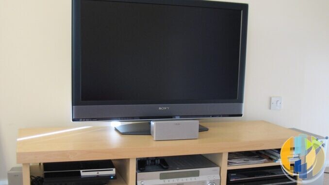 Sony BRAVIA TV on a light wood TV unit with a silver Sony AV receiver, PlayStation 3 and recorder on the shelves below