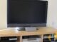 Sony BRAVIA TV on a light wood TV unit with a silver Sony AV receiver, PlayStation 3 and recorder on the shelves below