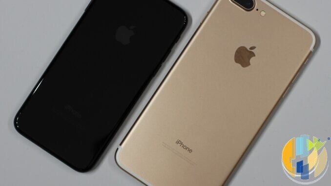 Jet black iPhone 7 and gold iPhone 7 Plus lying face down side by side on a light grey surface, showing their rear cameras and Apple logos