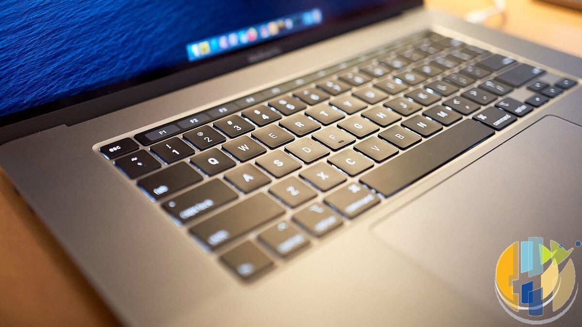 Close up of the keyboard and screen edge of a 2019 16 inch MacBook Pro, an Intel based Mac, on a wooden table